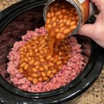 Pour canned baked beans over raw ground beef, together with 3 ingredients