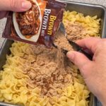 Pour brown gravy mix and these 3 ingredients over egg noodles into a baking pan